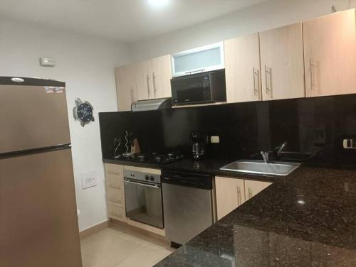 a kitchen with a sink and a stove and a refrigerator at Casa Arcoíris: Espectacular casa en Cartagena con Acceso directo a la Playa in Cartagena de Indias