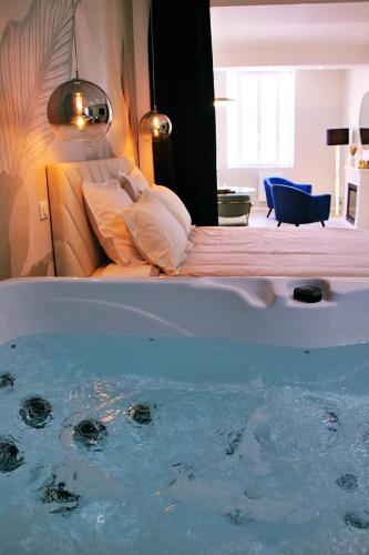 - une baignoire dans une chambre avec un lit dans l'établissement Appartement luxueux avec Jacuzzi privatif, à Roanne