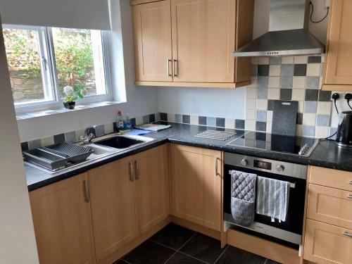 cocina con armarios de madera, fregadero y fogones en Briscoe Lodge Self Catering Apartments, en Windermere