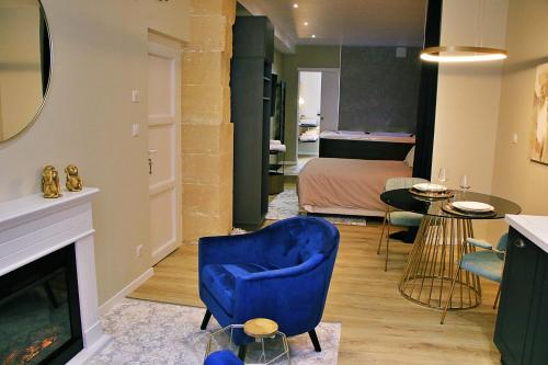 una sala de estar con una silla azul y un dormitorio en Appartement luxueux avec Jacuzzi privatif en Roanne