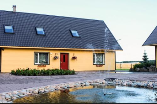 a yellow house with a pond in front of it at Käopesa Kodumajutus in Põlva