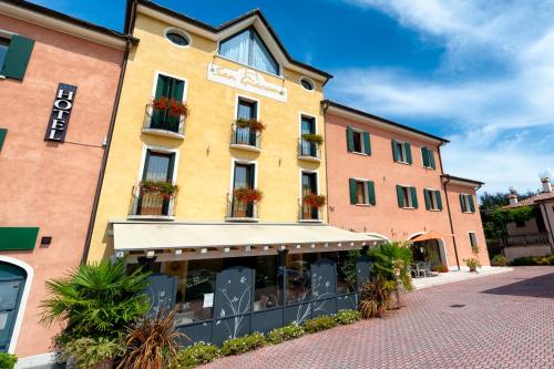 a yellow building with potted plants on the windows at Wine Hotel San Giacomo Activity & Wellness in Paderno del Grappa