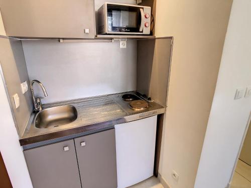 une petite cuisine avec un évier et un micro-ondes dans l'établissement Studio Carré d'Or. 2 mins from the Croisette. 143, à Cannes