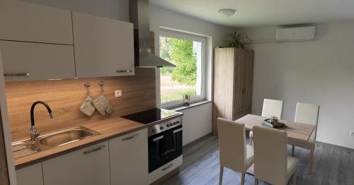 a kitchen with white cabinets and a sink and a table at GreenRiver Apartment in Spodnje Gorje