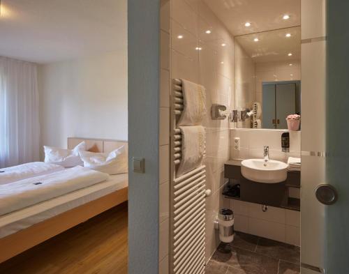 a bedroom with a bed and a sink and a mirror at Gästehaus Goethe in Staufen im Breisgau