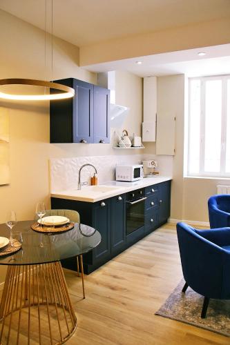 une cuisine avec des armoires bleues et une table et des chaises dans l'établissement Appartement luxueux avec Jacuzzi privatif, à Roanne