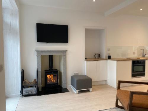a living room with a fireplace with a television and a stove at Hugmish in Tighnabruaich