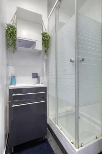 une salle de bain avec une douche en verre et un lavabo dans l'établissement Studio au cœur des Puces et à quelques mètres de Paris, à Saint-Ouen