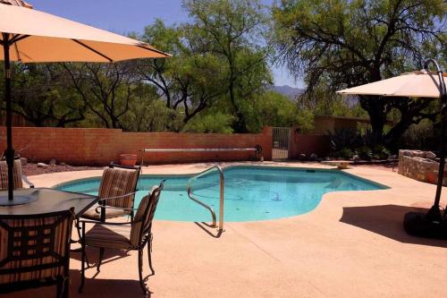 una piscina con mesa, sillas y sombrilla en Casa Saguaro - Newly Remodeled, Pool and Mtn Views, en Tucson
