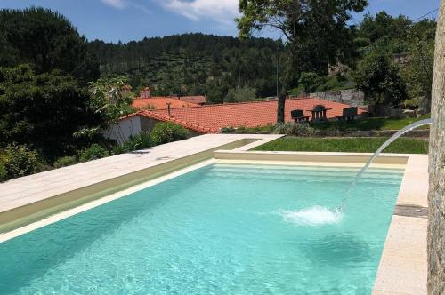 a swimming pool with a water fountain at Casas Viriatus in Paredes de Coura