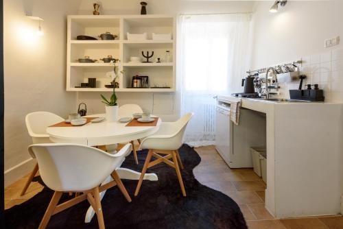 eine Küche mit einem Tisch und weißen Stühlen im Zimmer in der Unterkunft Appartamento studio e design in centro storico Sulmona in Sulmona