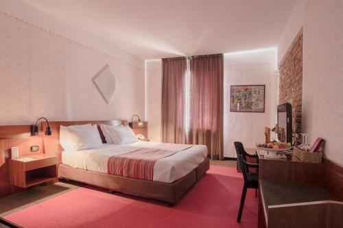 ein Hotelzimmer mit einem Bett und einem Schreibtisch mit einem Stuhl in der Unterkunft Cangrande Hotel in Lazise