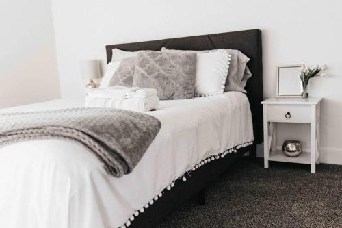 a white bed with a black frame and a white table at 2 CONDOS next to each other Perfect for GROUPS in Logan