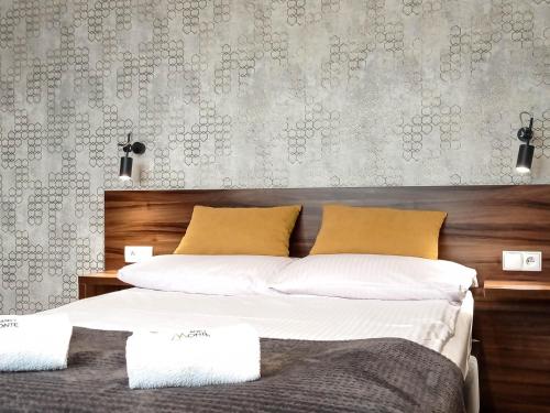 a bedroom with a bed with white sheets and yellow pillows at Willa Monte in Wisła