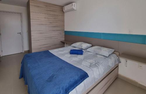 a bedroom with a bed with a blue blanket at Areias do Mar 2 Quartos, Charmoso e Completo in Barra de São Miguel