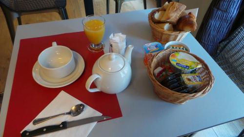 una mesa con una taza de café y una cesta de pan en Hôtel Le Cambronne, en Nantes