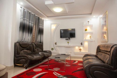 - un salon avec 2 fauteuils en cuir et une télévision dans l'établissement Calme et securité, à Dakar
