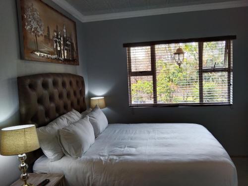 a bedroom with a white bed and two windows at Menlyn Mews Guesthouse in Pretoria
