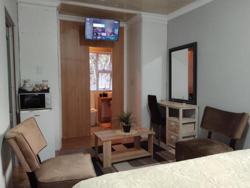 a room with a bed and a table and a mirror at Menlyn Mews Guesthouse in Pretoria