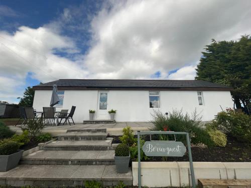 a white house with a sign in front of it at Unique countryside stay in Dundrod