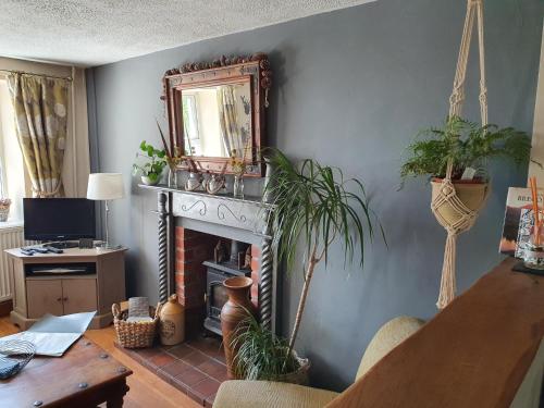 a living room with a fireplace and a mirror at Wales' Highest Village - The Chartist Cottage - Trefil in Tredegar