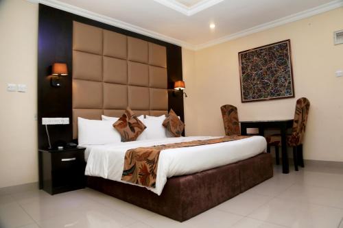 a hotel room with a large bed and a desk at CLASS COTTAGE in Ikeja