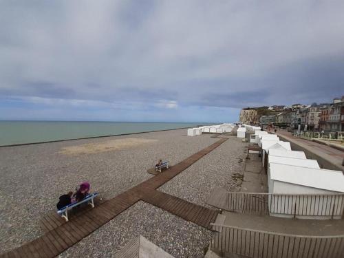 una persona seduta su una panchina in spiaggia di Studio lumineux 50 m de la plage a Mers-les-Bains