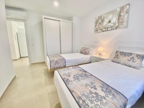 two beds in a room with white walls at Sonrisa Deluxe Apartments, Levante in Benidorm