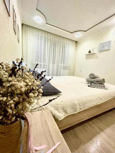 1 dormitorio con 1 cama y un jarrón de flores en Роскошные апартаменты в центре, en Temirtaū
