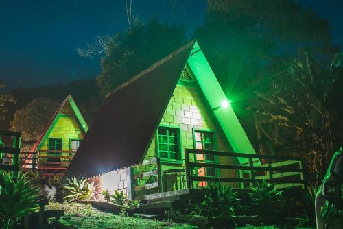 una casa illuminata di notte con luce verde di Pousada Recanto da Lua a Caparaó Velho