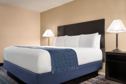 a large bed in a hotel room with two lamps at Super 8 by Wyndham Lindsay Olive Tree in Lindsay