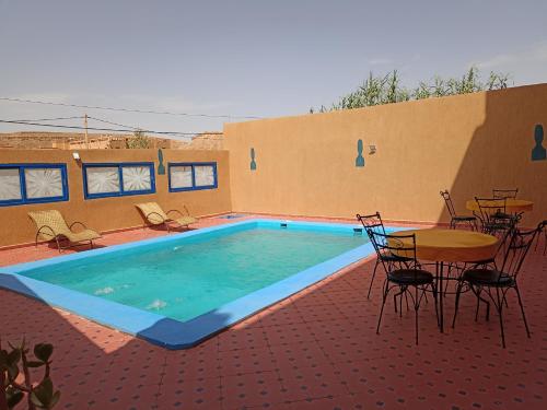 a swimming pool with chairs and a table and a table and a table and chairs at La Baraka Auberge in Aït Benhaddou