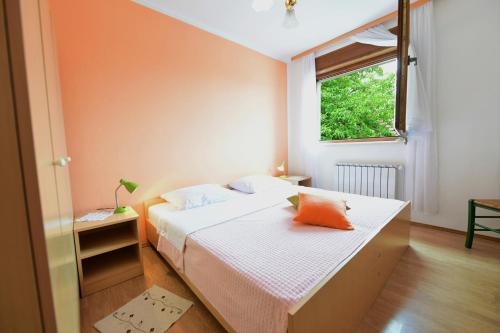 1 dormitorio con 1 cama con pared de color naranja en Apartments Alan, en Saborsko