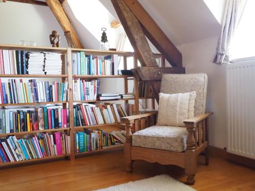 une étagère remplie de livres à côté d'une chaise dans l'établissement Les Vergers de Cussy, à Cussy-en-Morvan