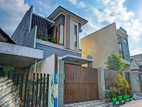 una casa con una puerta de madera y una valla en SPOT ON 91530 Sumpil Syariah, en Malang