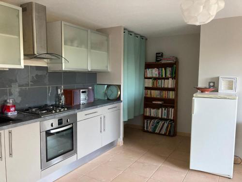 une cuisine avec des placards blancs et une étagère à livres dans l'établissement Logement indépendant, de plain pied, à Rodez Aveyron, à Onet le Château