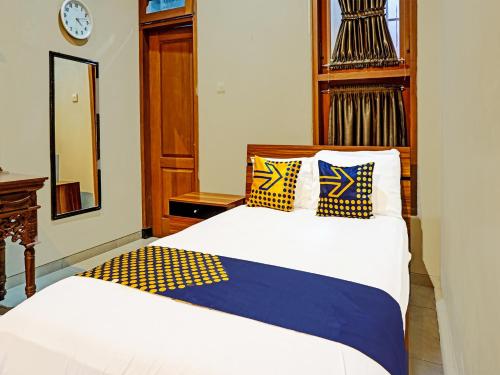 1 dormitorio con 2 camas con almohadas amarillas y azules en SPOT ON 91530 Sumpil Syariah en Malang