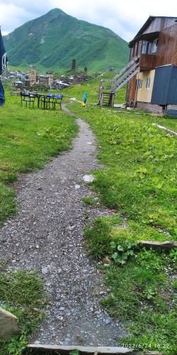 a gravel path in a field with benches and a house at Vila Latphari in Ushguli in Ushguli