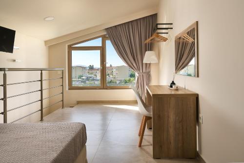 a bedroom with a bed and a desk and a window at Grapevines Hotel in Alikanas