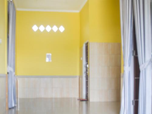 La salle de bains est pourvue d'une douche et d'un mur jaune. dans l'établissement SPOT ON 91463 Obby Guest House, à Balikpapan
