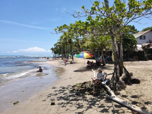a man sitting on a bench on a beach at HOTEL, VILLAS y GLAMPINGS MYA -PUERTO VIEJO, Limon, CR in Puerto Viejo