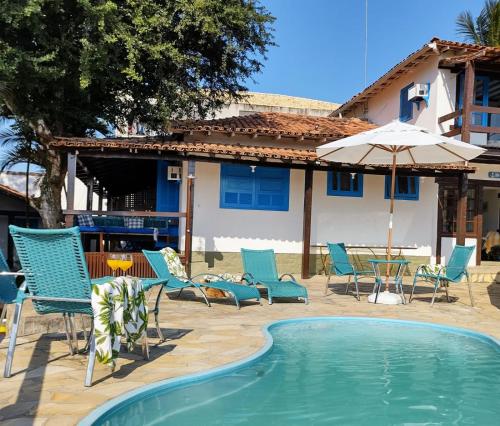 uma piscina com cadeiras, uma mesa e um guarda-sol em Mar de Maria Pousada em Búzios