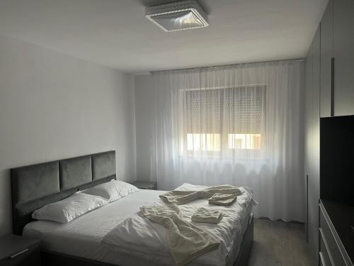 a white bedroom with a bed and a window at Apartament 5ive in Tăşnad