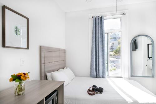 a white bedroom with a bed with a window at Hermosa Hotel in Avalon