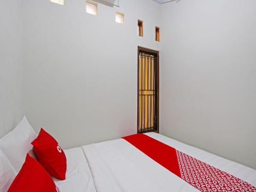 Schlafzimmer mit einem roten und weißen Bett und einem Fenster in der Unterkunft OYO 91487 Ib Homestay Syariah in Tegal