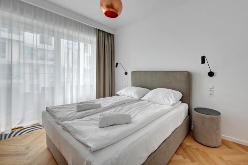 a white bedroom with a large bed with white sheets at Wave Apartments - Yacht Park 2 in Gdynia