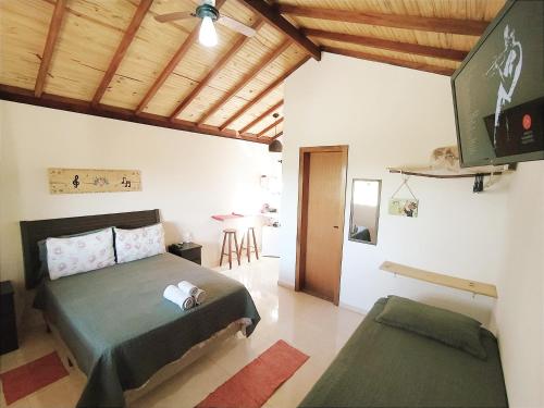 a bedroom with a bed and a flat screen tv at Toca dos Coelhos Chalés in Carrancas