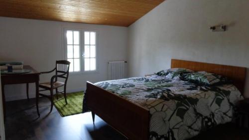 ein Schlafzimmer mit einem Bett, einem Tisch und einem Stuhl in der Unterkunft Maison indépendante sur grand terrain clos in Thénezay