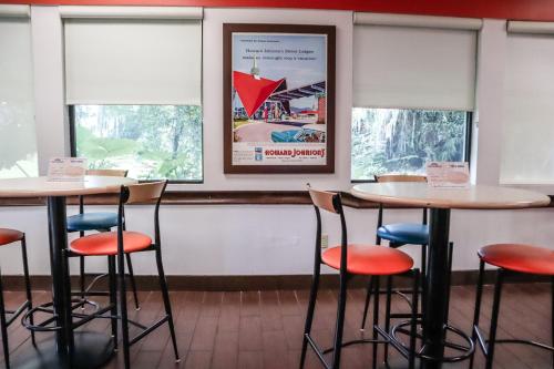 two tables and chairs in a restaurant with windows at Howard Johnson by Wyndham Ocala FL I-75 in Ocala