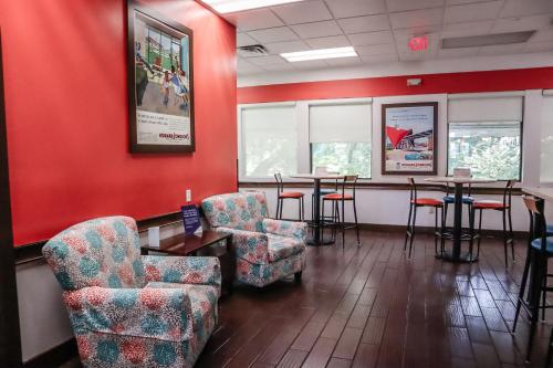 a waiting room with chairs and tables and red walls at Howard Johnson by Wyndham Ocala FL I-75 in Ocala